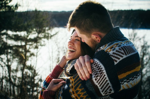 Free stock photo of Joyful cute couple embraces. Young man in a sweater hugs a girl from behind background in winter. The concept of a successful relationship and happy moments - Reshot