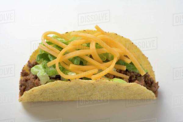 Taco filled with mince & cheese on brown background - Stock Photo - Dissolve