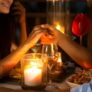 Romantic couple holding hands together over candlelight during romantic dinner - Arrowhead Inn