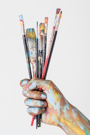Premium Photo | Hand holding brushes stained with paint
