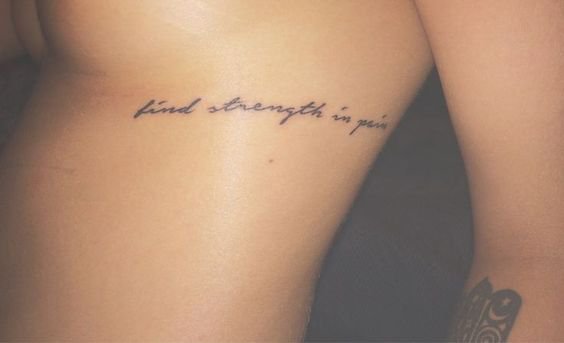 “find strength in pain” rib tattoo